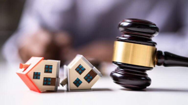 Two toy houses next to a striking gavel