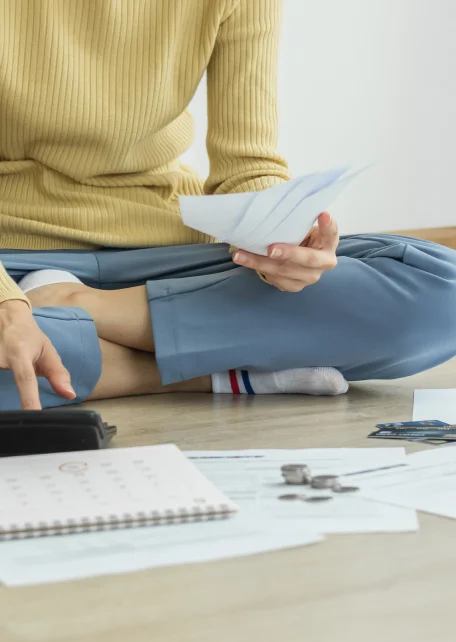 A person sitting on the floor with papers and calculator