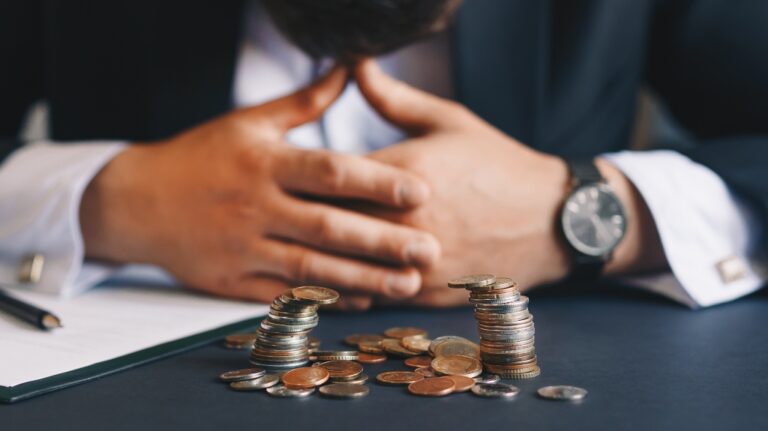 sad man lying on table near coins