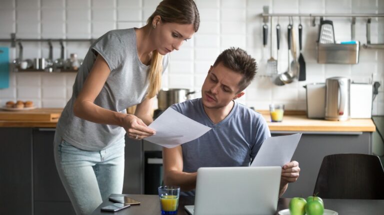 worried couple reading papers in kitchen